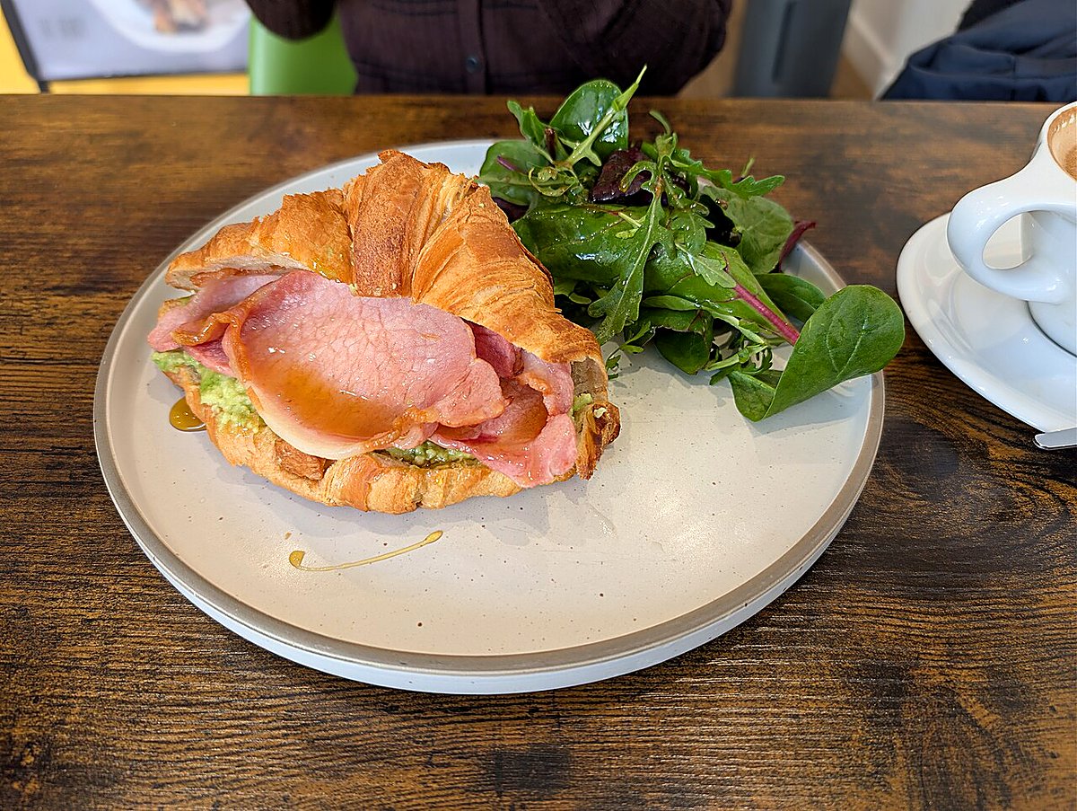 A croissant breakfast sandwich filled with bacon, avocado and egg