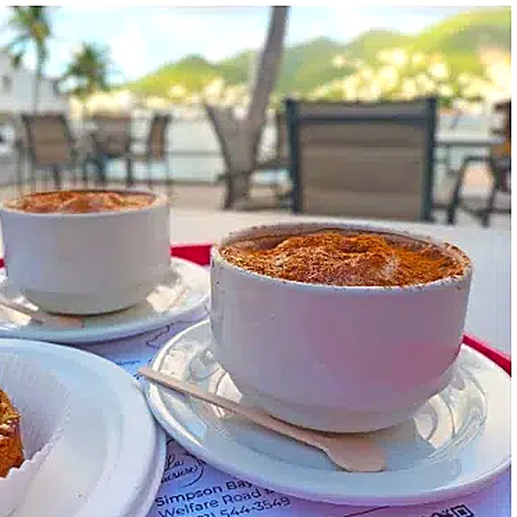 Two cappuccinos dusted with cocoa on a terrace table overlooking the lagoon at La Sucrière