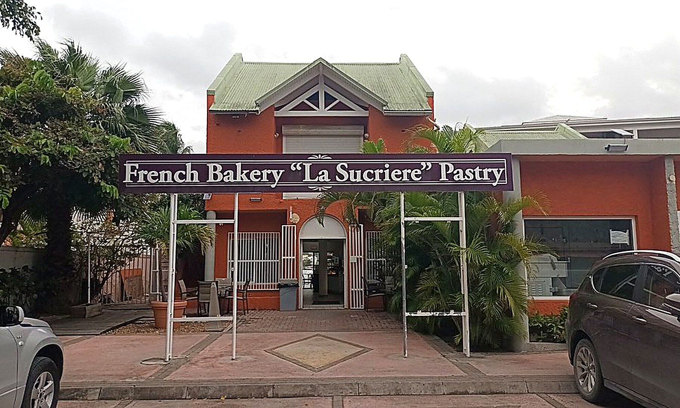 The original La Sucrière storefront on Welfare Road, Cole Bay — orange building with the French Bakery La Sucriere Pastry sign