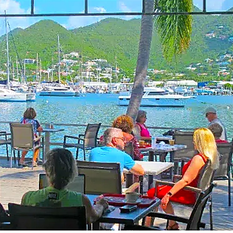 Guests at La Sucriere's lagoon-side terrace with yachts beyond
